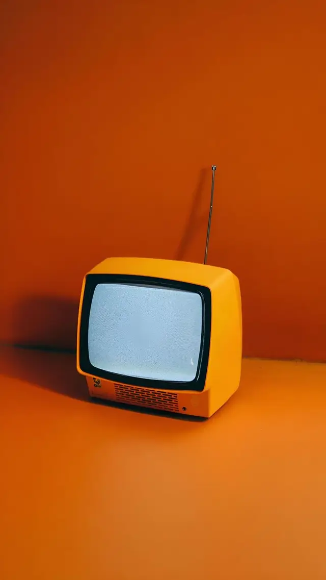 Orange retro portable TV with static screen on seamless orange backdrop