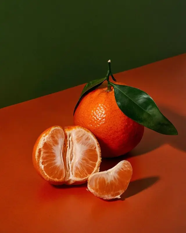 Mandarin orange with leaf and peeled segments — studio still life