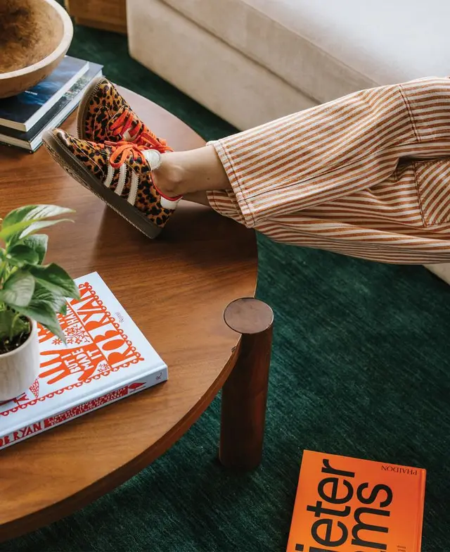 Leopard-print sneakers and striped pants on walnut round coffee table