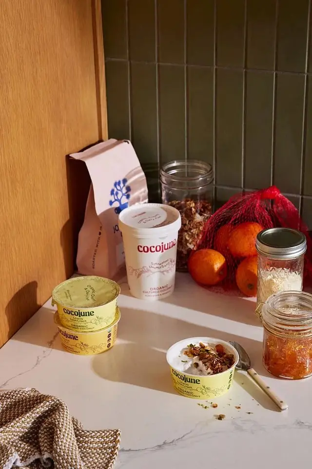 Cocojune yogurt breakfast with mandarins, granola, and jam on marble countertop