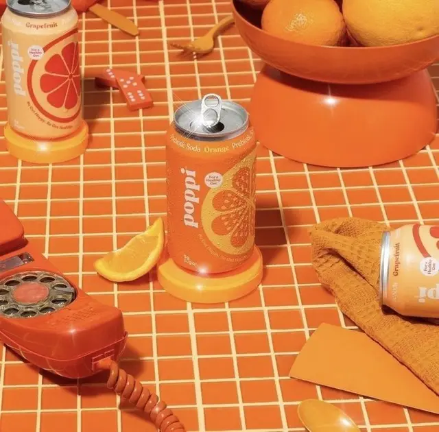 Poppi grapefruit soda can styled on orange-tiled tabletop