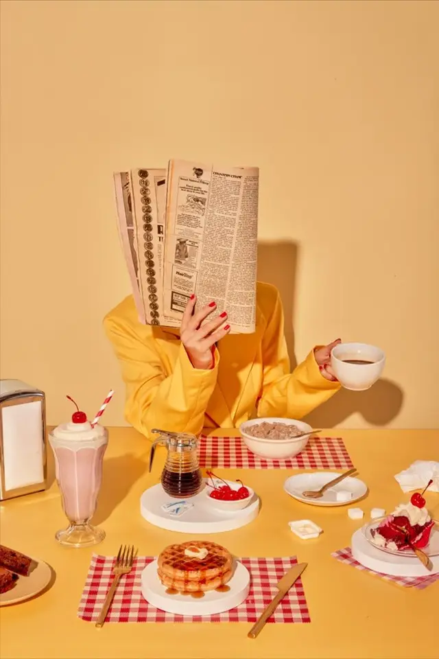 Yellow-blazer breakfast scene with waffle, milkshake and newspaper