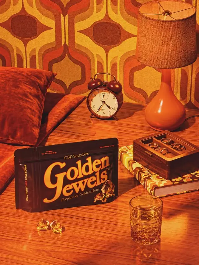 Golden Jewels CBD packaging on 1970s-style bedside table
