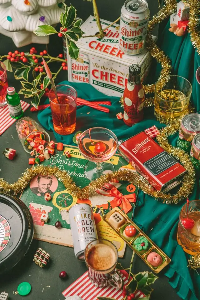 Festive tabletop with Shiner Holiday Cheer six-pack, cocktails and confections