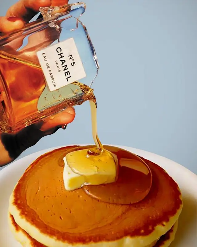 Chanel No.5 bottle pouring amber liquid onto buttered pancakes