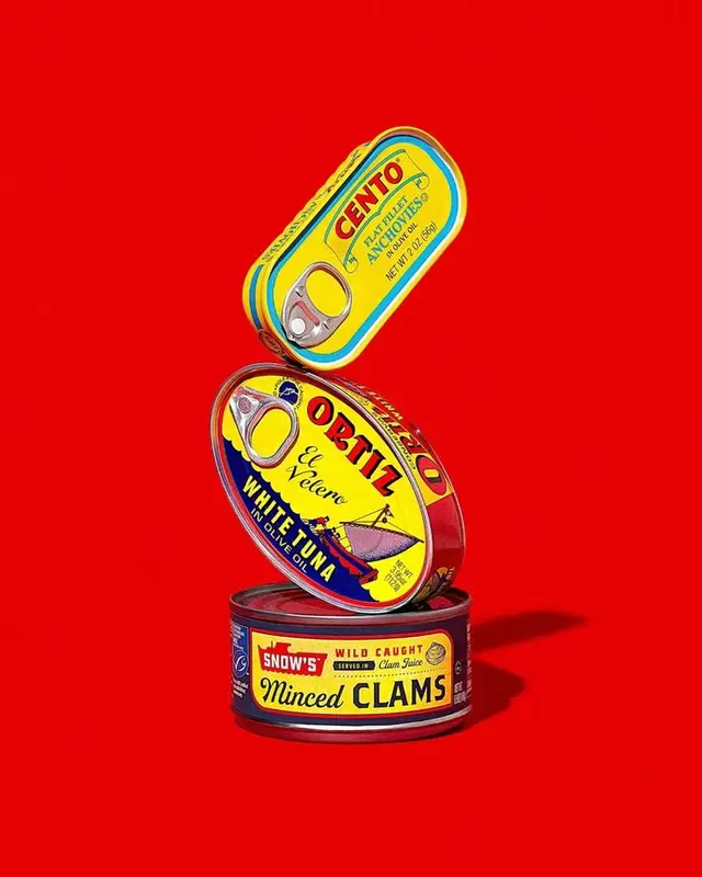 Stacked vintage seafood tins on bright red background