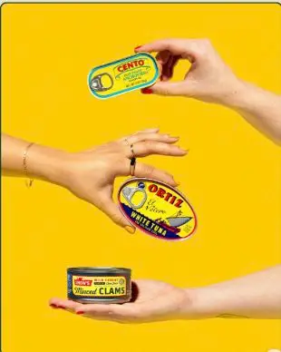 Studio photo — three vintage canned seafood tins (CENTO, ORTIZ) on yellow background