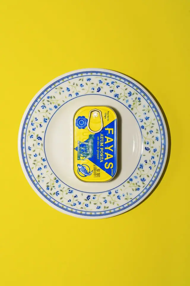 FAYAS yellow tin on blue-floral china — flat-lay on yellow background