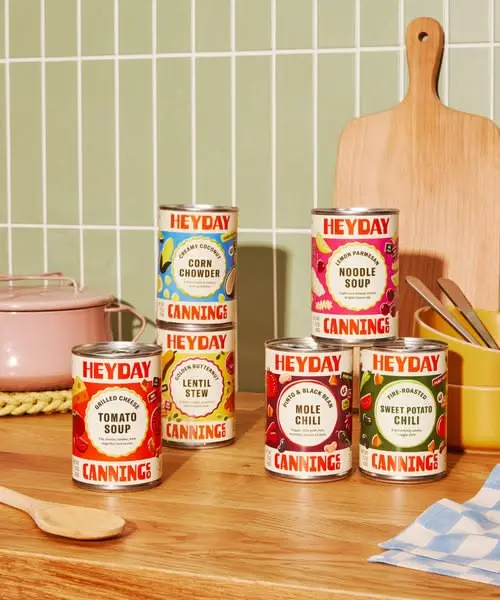 HEYDAY canned soups and chilis on wooden countertop with pastel tile backsplash