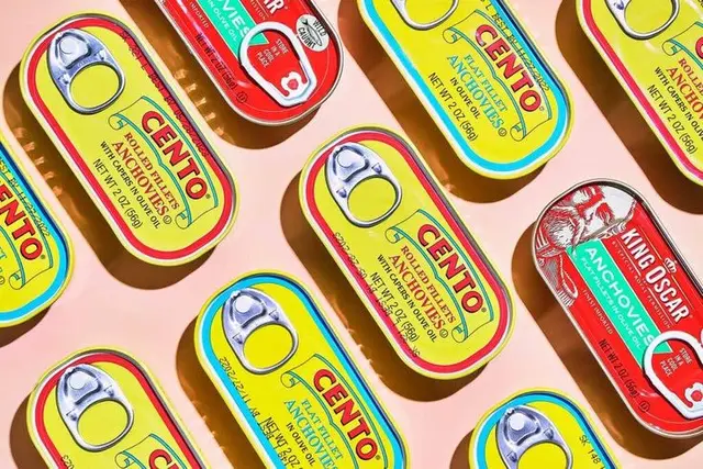 Flat-lay of CENTO and KING OSCAR anchovy tins on pink background