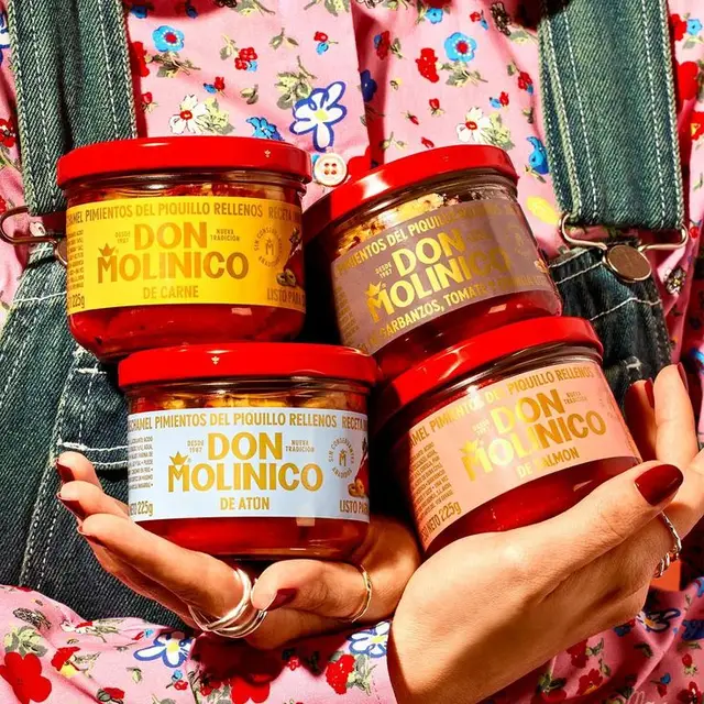 Don Molinico stuffed piquillo pepper jars held against floral shirt and denim overalls