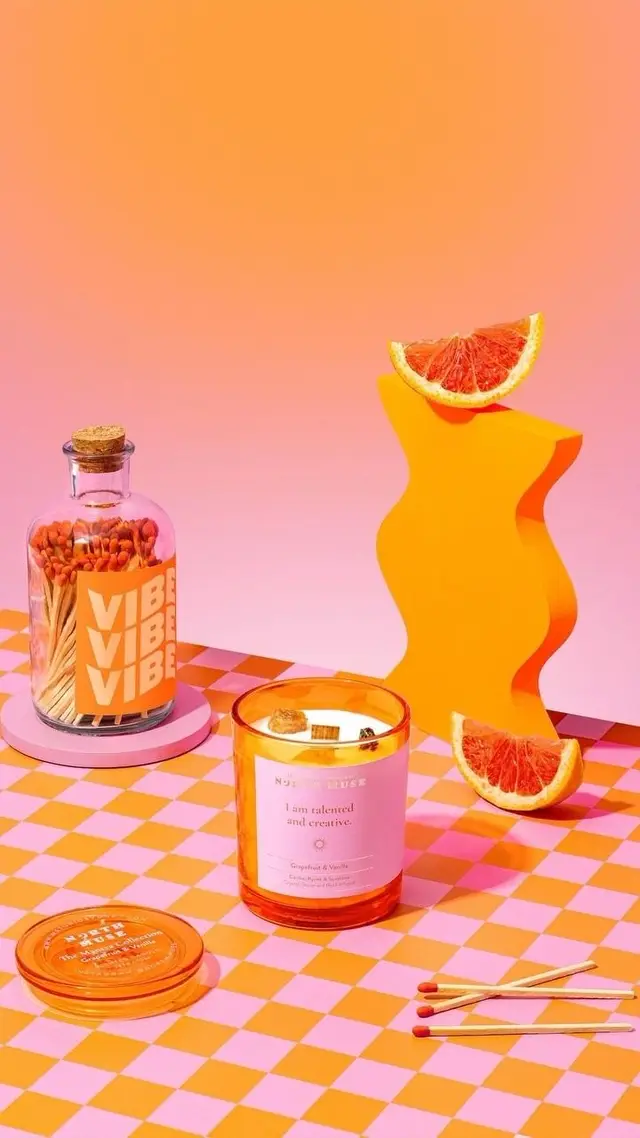 Grapefruit candle and 'VIBE VIBE VIBE' match jar — pink & orange still life