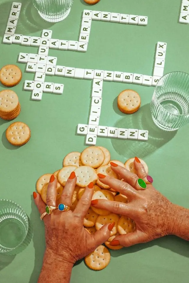 Green tabletop flatlay with crackers, letter tiles and colorful rings