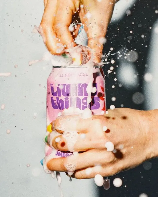 Hands opening pink 'LIQUID THINGS' soda can — foamy splash