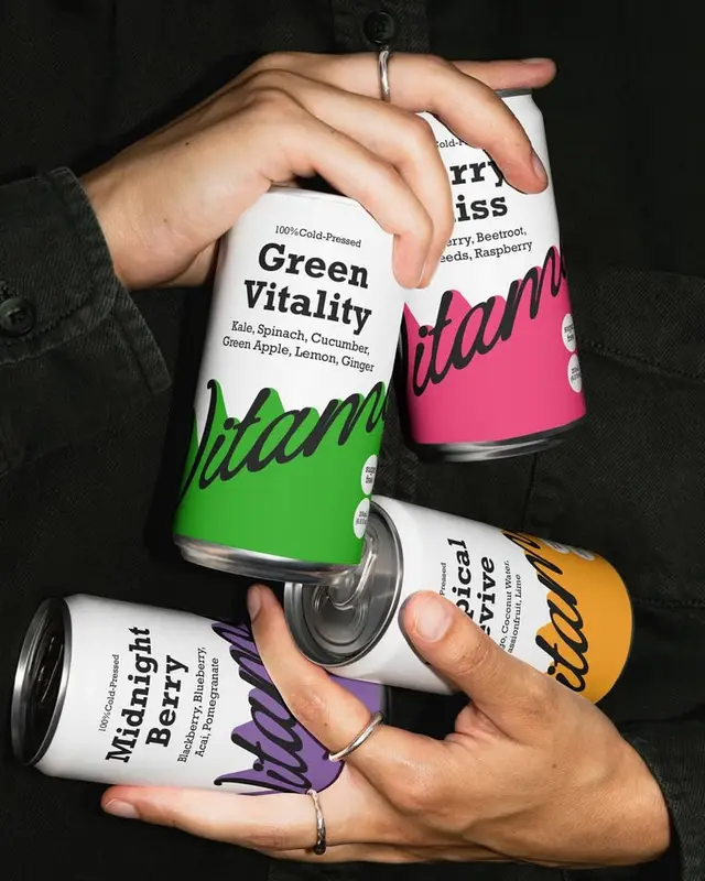 Color-blocked cold-pressed juice cans held in hands