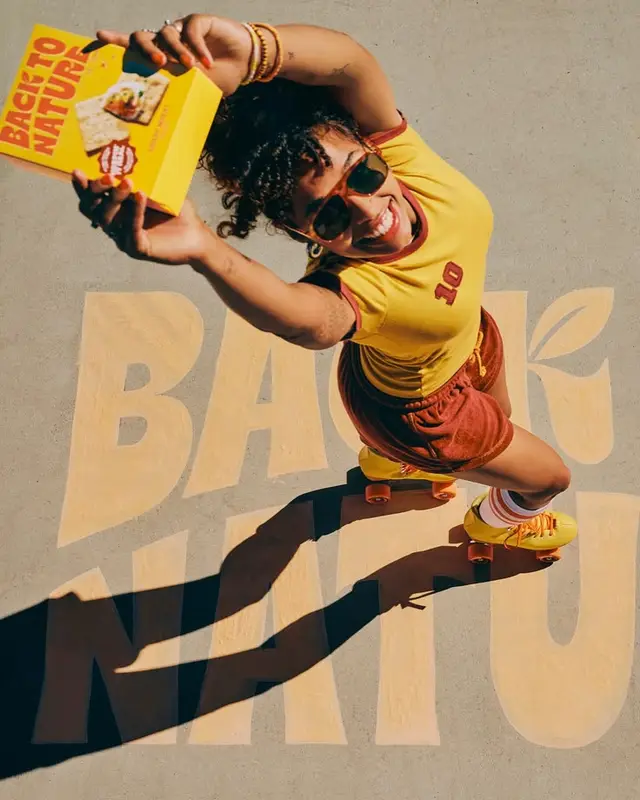 Overhead retro lifestyle photo — woman on yellow quad skates holding 'BACK TO NATURE' box