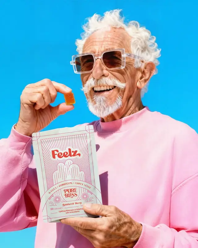 Older man holding Feelz "Pure Bliss" gummy and packaging against cyan backdrop
