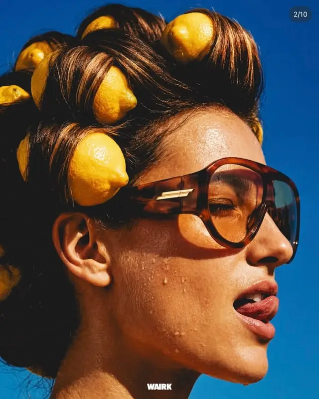Editorial close-up: model with lemons in rolled hair and tortoiseshell sunglasses