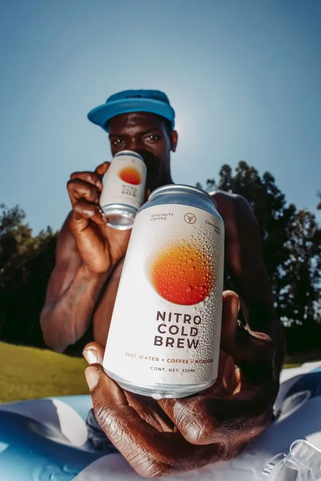 Nitro Cold Brew can held toward camera — low-angle summer product shot