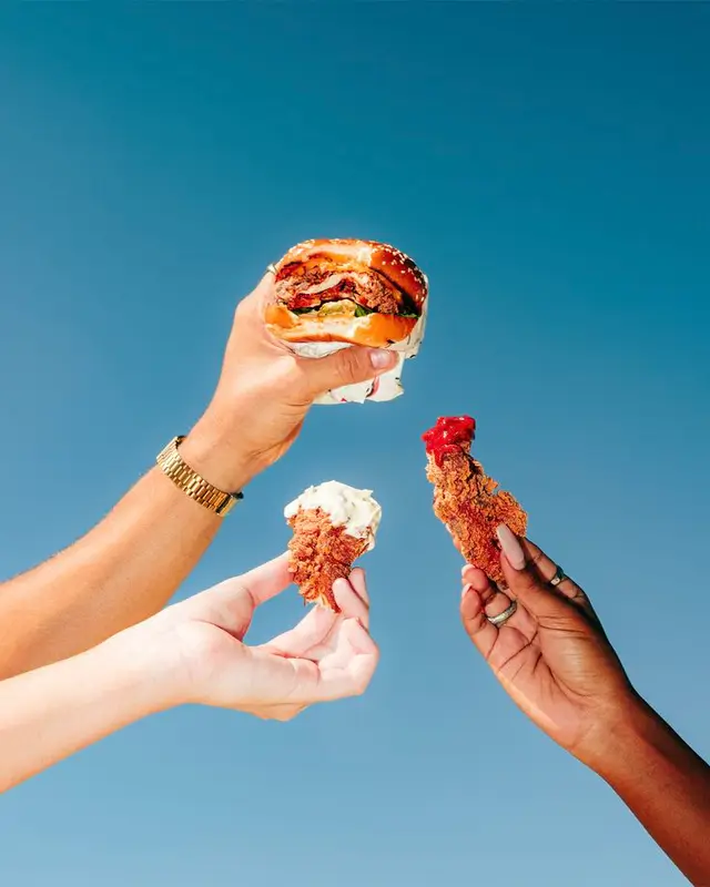 Sesame Burger and Fried Chicken Tenders Raised Against Clear Blue Sky