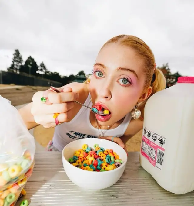 Wide-angle close-up of person eating multicolored ring cereal outdoors