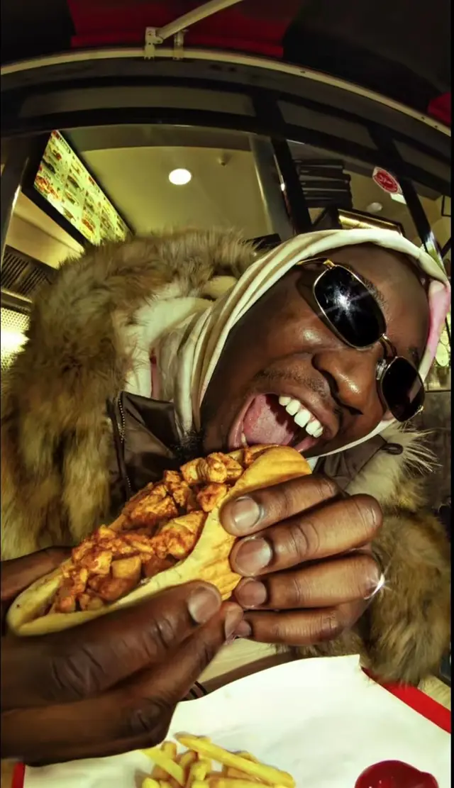 Person in fur-trimmed parka biting into loaded chicken taco at fast-food counter