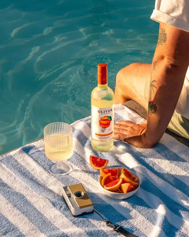 Poolside still life with OLIVER Blood Orange bottle and vintage camera
