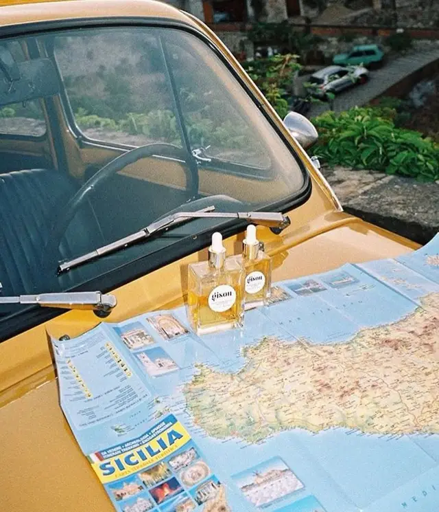 Yellow vintage car hood with Sicilia map and two glass dropper bottles