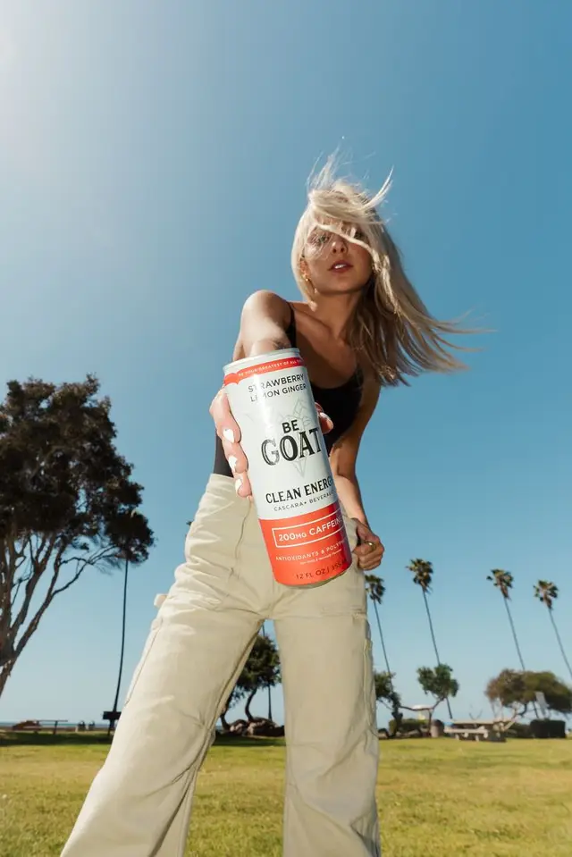 Low-angle lifestyle photo with BE GOAT Clean Energy can in sunny park
