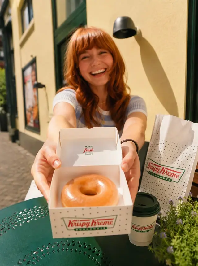 Krispy Kreme original glazed doughnut in branded box — outdoor cafe shot