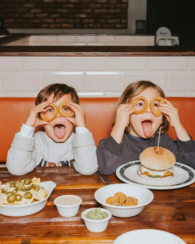 Children Playfully Eating Onion Rings and Burgers in Diner Booth