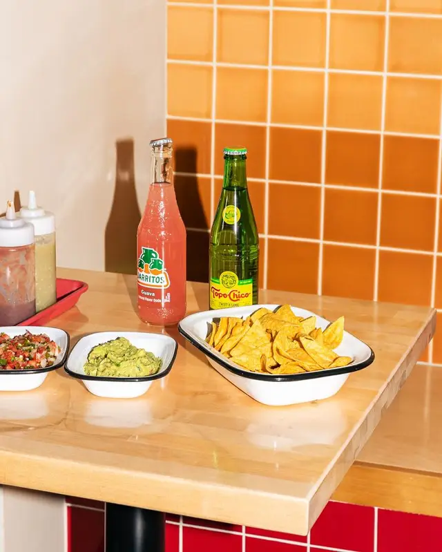 Jarritos Guava and Topo Chico with Chips, Guacamole & Salsa on Orange Tile Diner Table