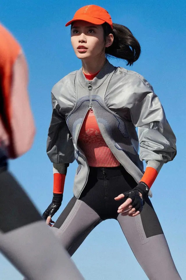 Sportswear editorial — orange cap, silver bomber jacket, color‑block leggings