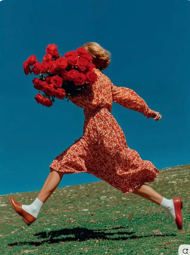 Leap with Red Roses — Model in Red Floral Dress Against Azure Sky