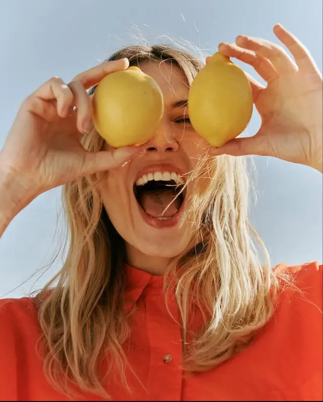 Playful summer portrait — woman holding lemons over her eyes