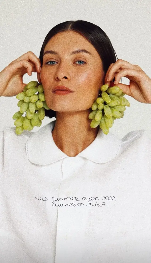 Editorial portrait — model with green grape 'earrings' and white collared blouse (New SUMM
