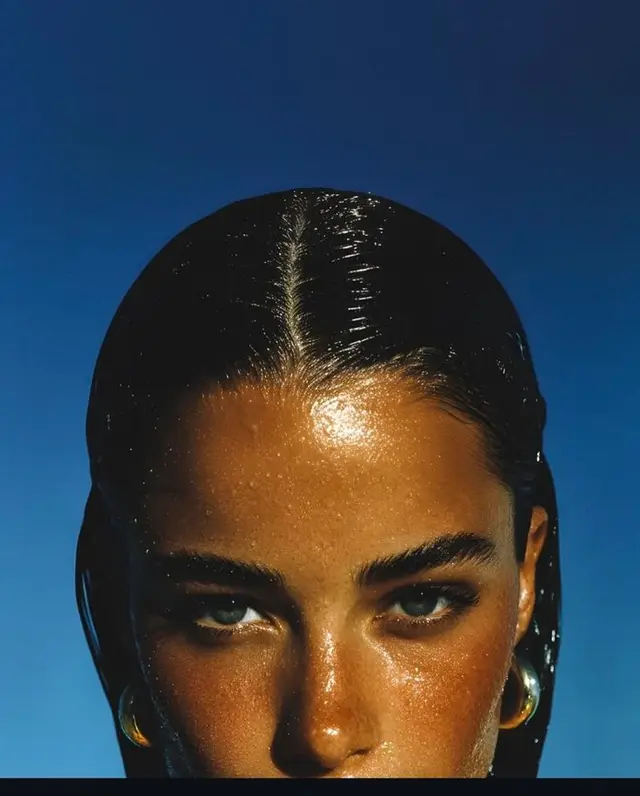 Editorial close-up: wet-look bronzed beauty with gold hoops