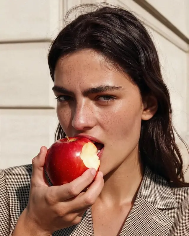 Close-up fashion portrait of woman biting a red apple