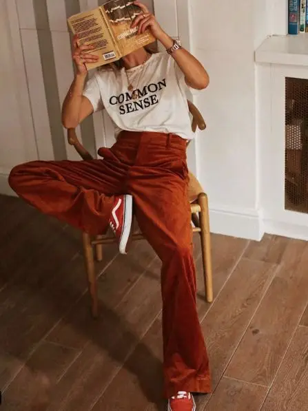White “COMMON SENSE” tee with rust corduroy wide-leg trousers and red canvas sneakers