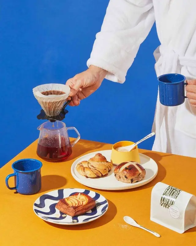 Morning pour-over coffee and pastries on mustard table with cobalt backdrop
