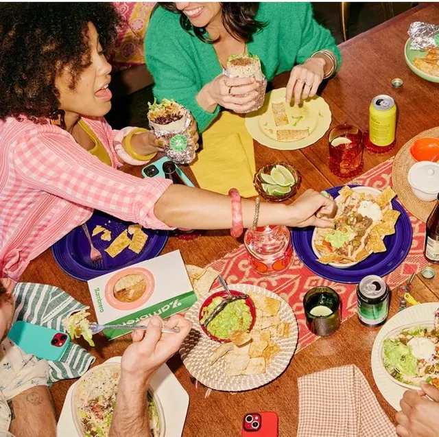 Overhead: Friends sharing Mexican‑style nachos, burritos and guacamole