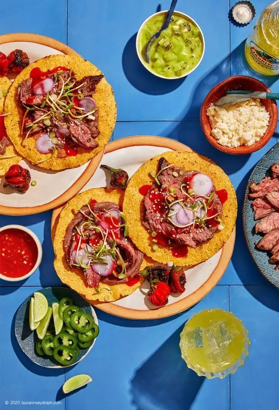 Overhead flatlay: Steak tacos on corn tortillas with radish and microgreens