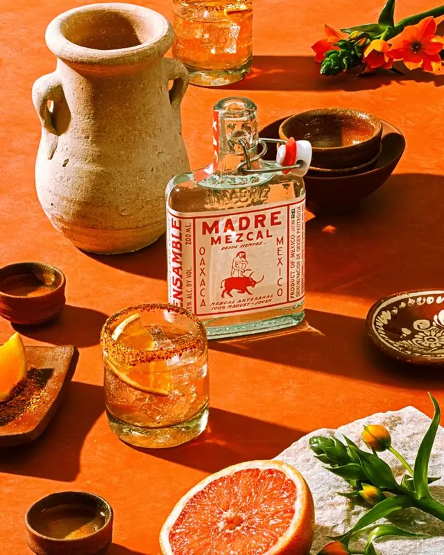 Madre Mezcal bottle still life on terracotta table with cocktail and grapefruit