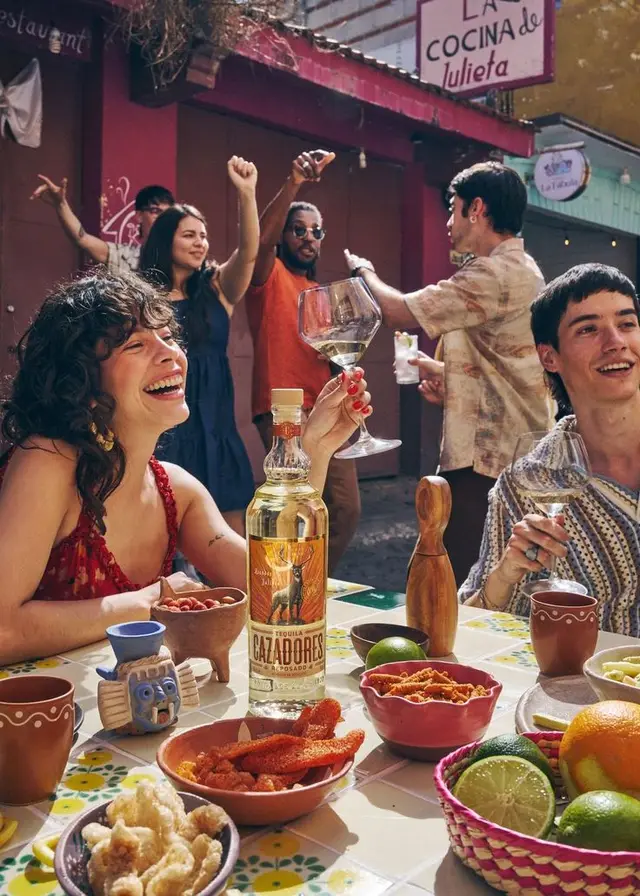 Friends sharing Tequila Cazadores and snacks outside 'La Cocina de Julieta'