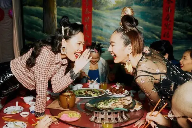 Lively Chinese banquet — two women laughing across a round table with whole fish