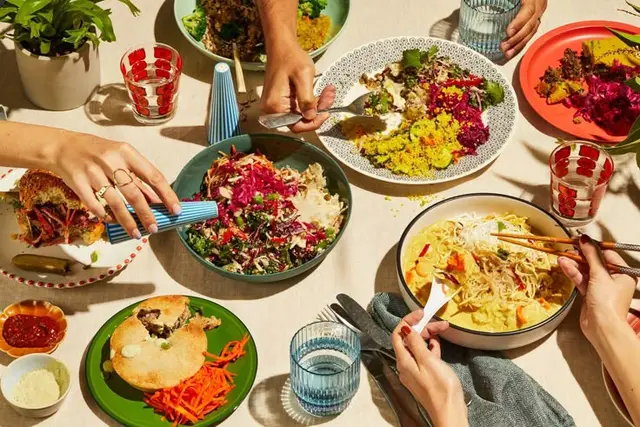 Overhead communal meal with colorful salads, couscous and noodle bowl