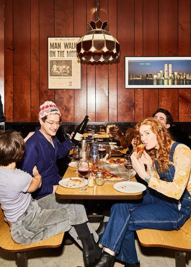 Friends Sharing Pizza at Retro Wood‑Paneled Diner Booth