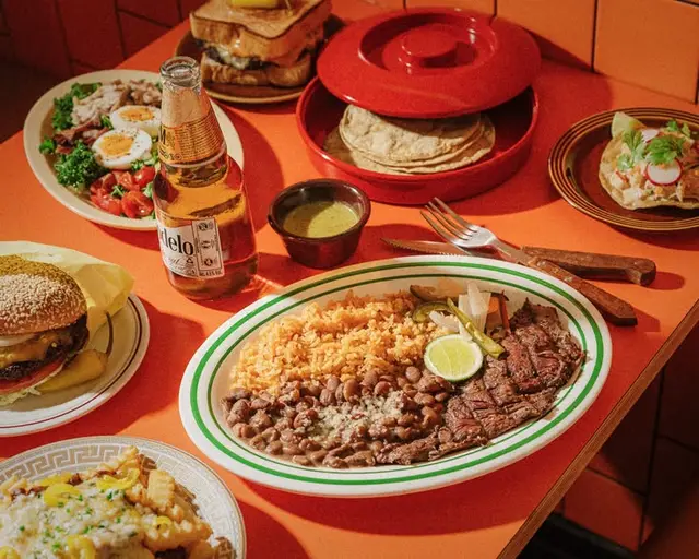 Carne asada plate with rice, beans and tortillas on orange diner table