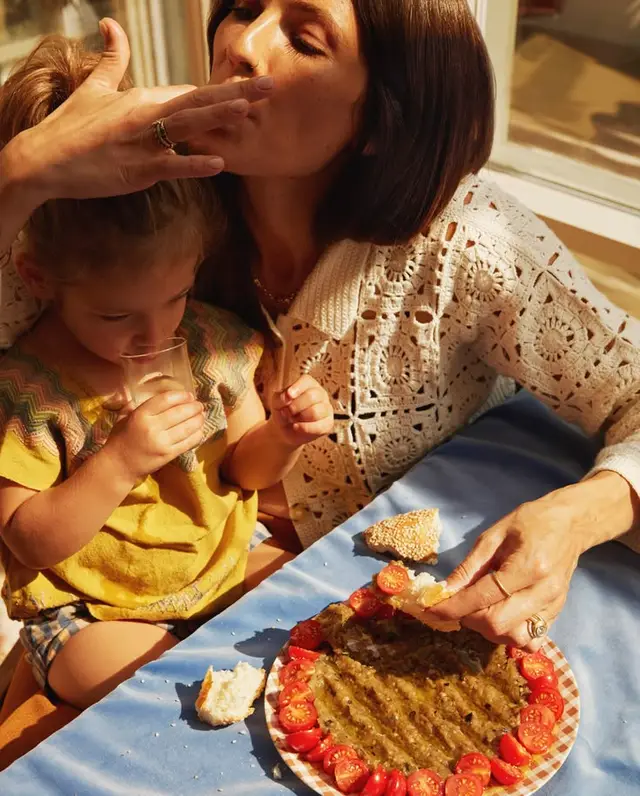 Sunlit family snack with crochet cardigan and tomato‑ringed dip