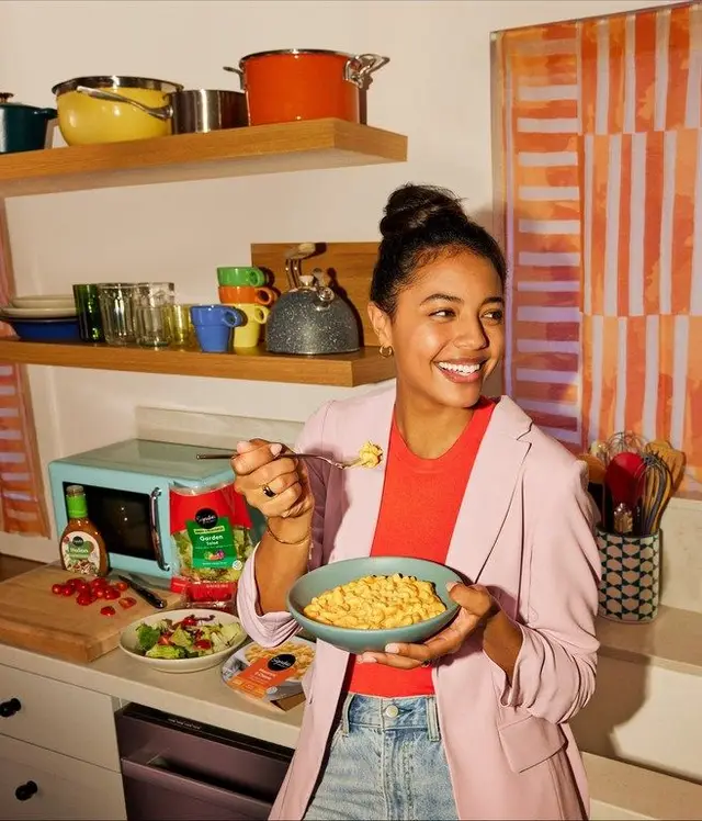 Person eating macaroni and cheese in a colorful retro kitchen
